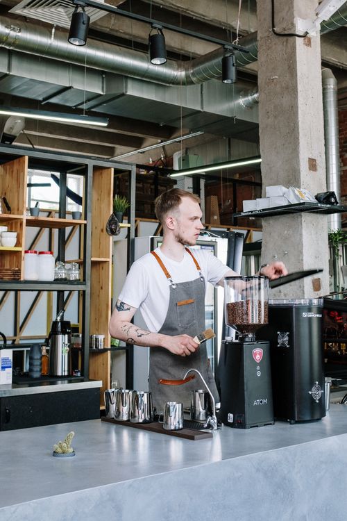 Free A young male barista prepares coffee in a stylish and modern café interior. Stock Photo
