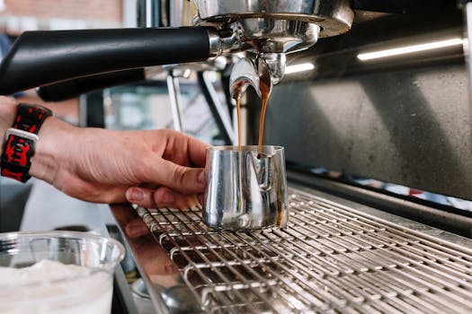 Barista preparing espresso with a machine, pouring freshly brewed coffee into a metal pitcher.