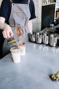 Barista pouring iced lattes with precision in a stylish café setting.