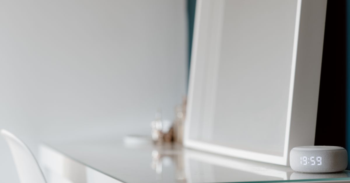 Elegant minimalist white desk setup with a digital clock in a serene setting.