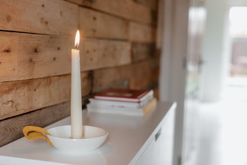 Glänzende Kerze Nahe Stapel Bücher Und Holzwand