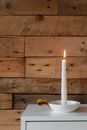 Bright burning candle near wooden wall in house
