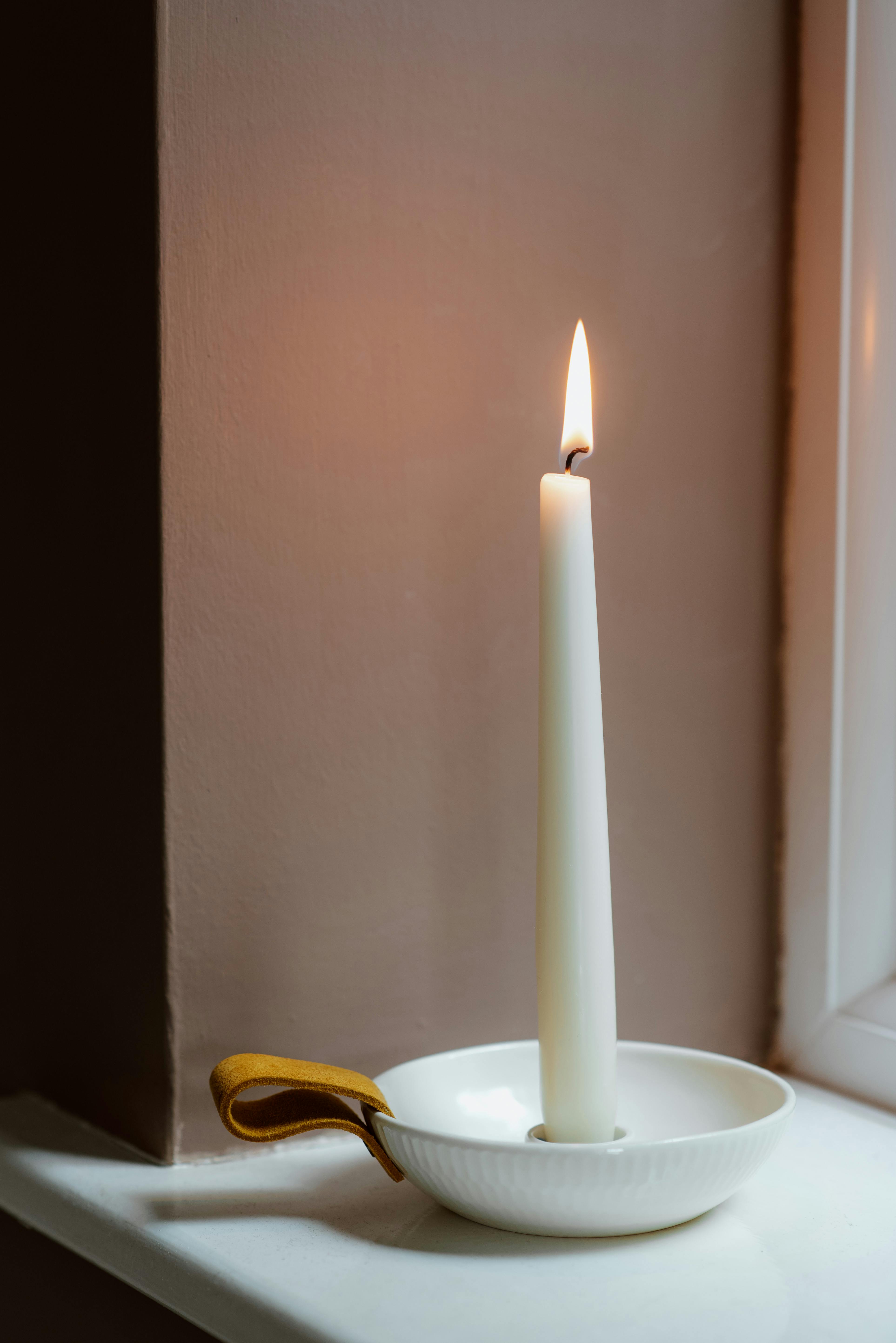 shiny candle in bowl on windowsill in house