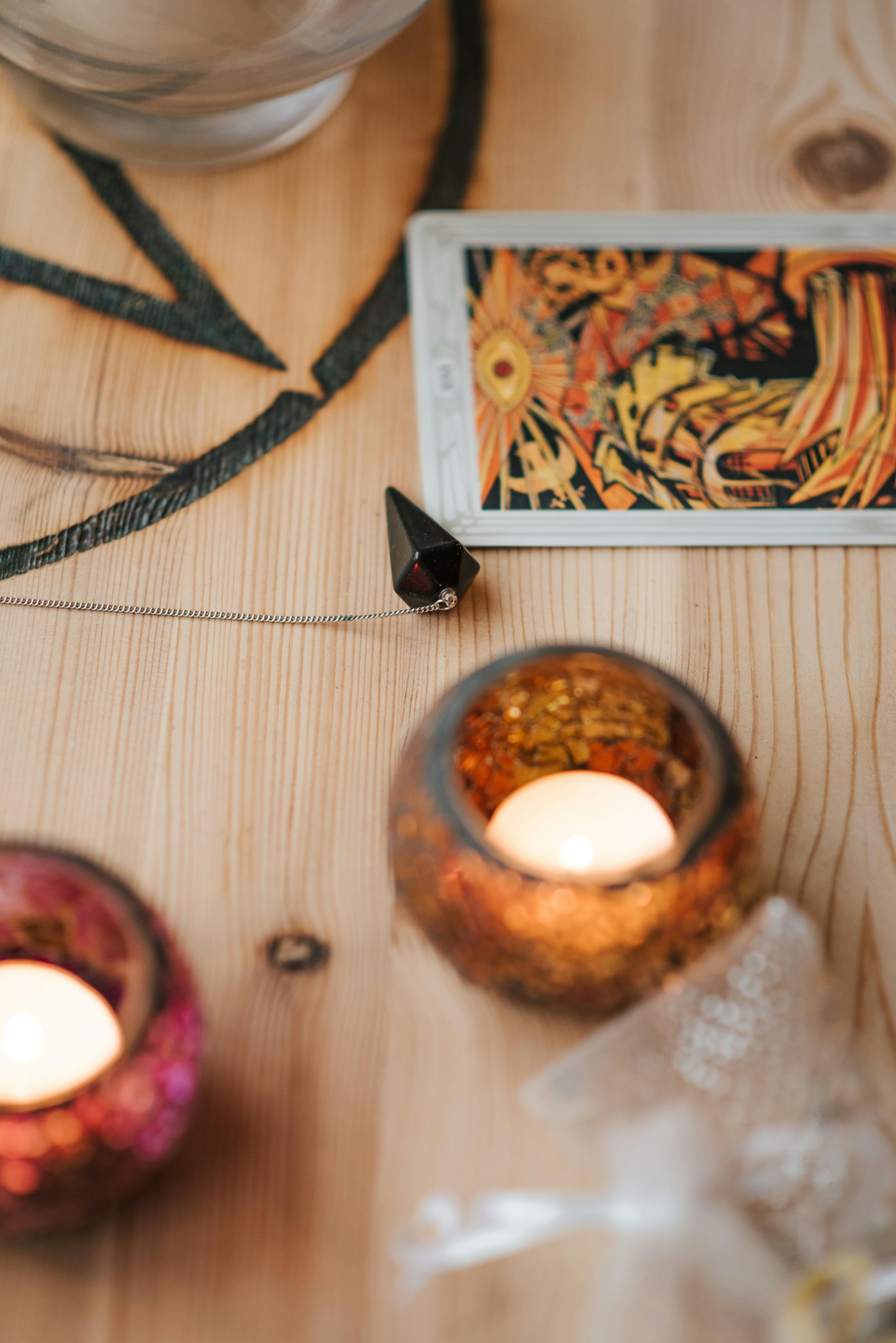 burning candles near tarot card on wooden table