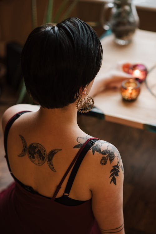 Faceless tattooed soothsayer with burning candles at home