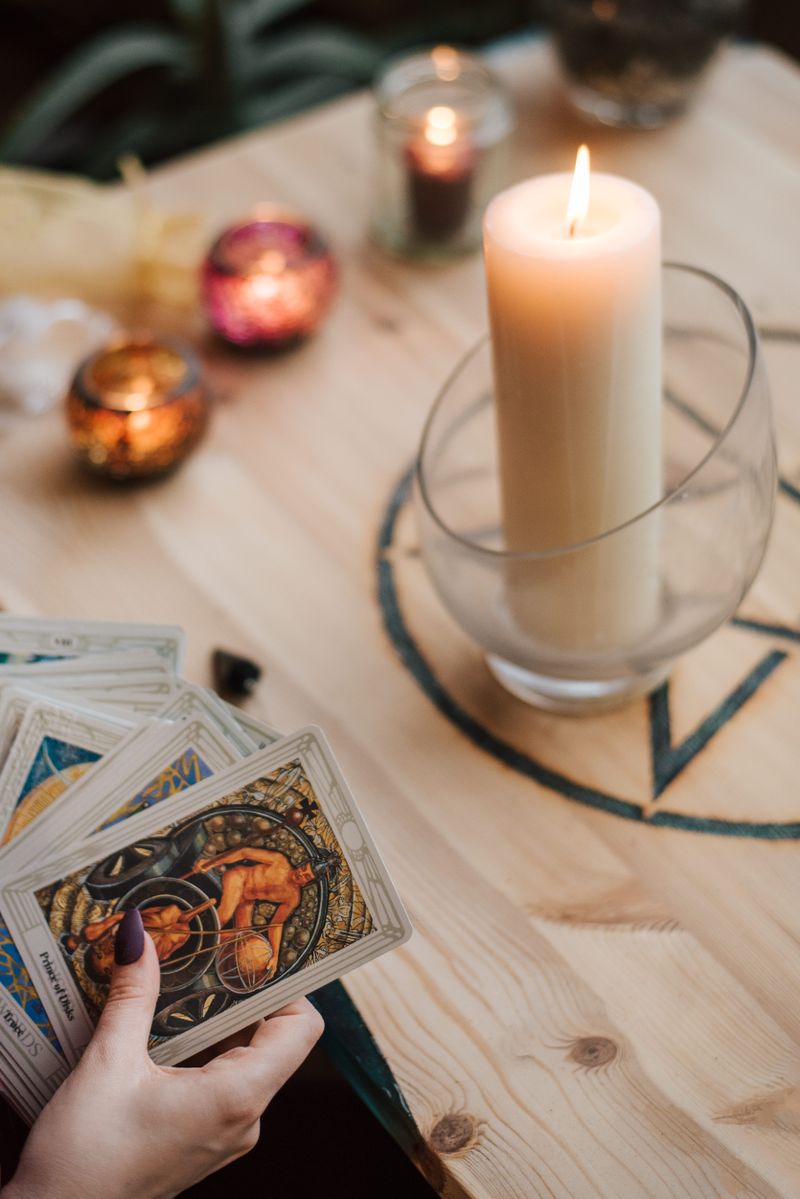 tarotkort och ett tänd ljus på ett skrivbord