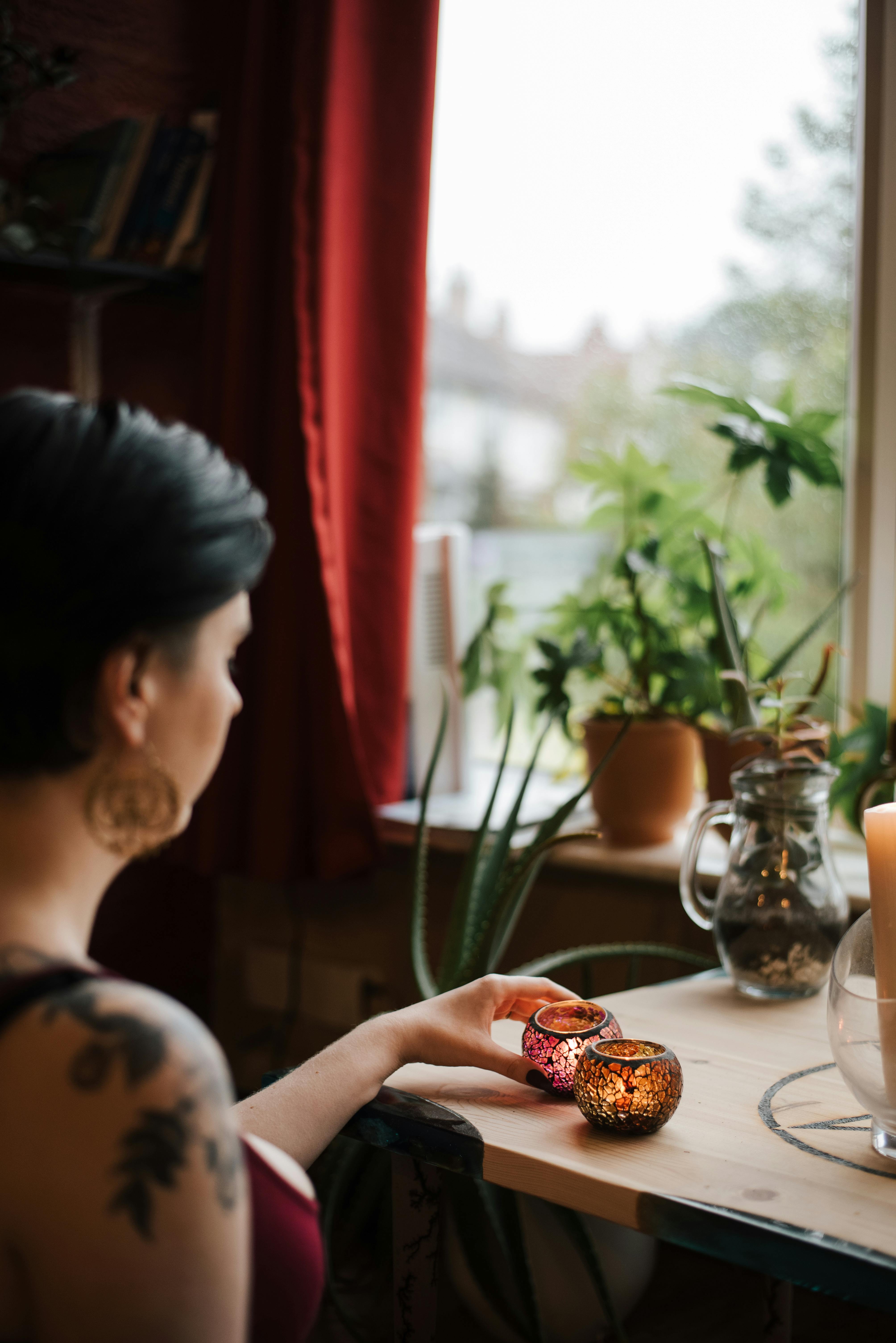 unrecognizable soothsayer with shiny candles near house window