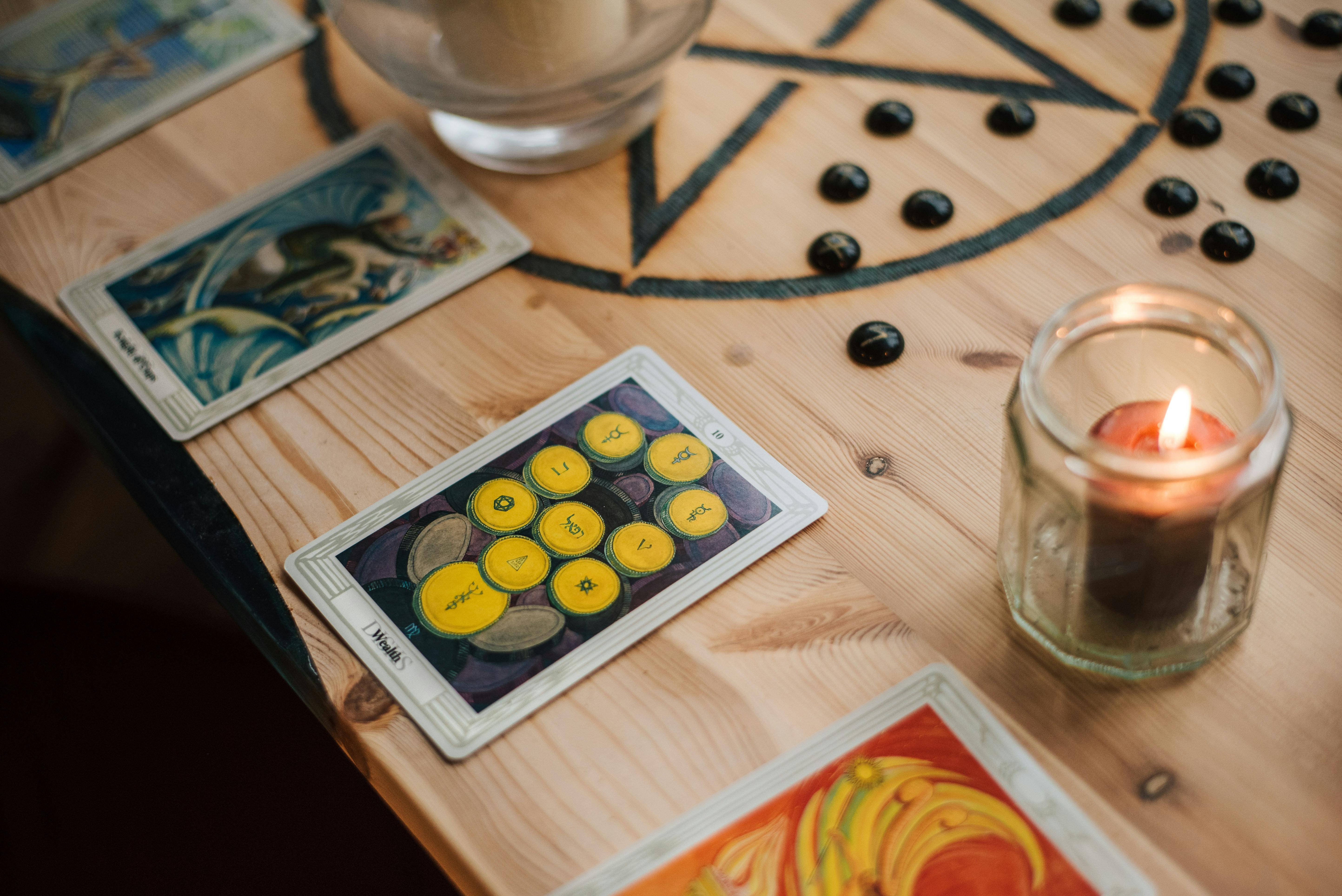 burning candle near tarot cards on table