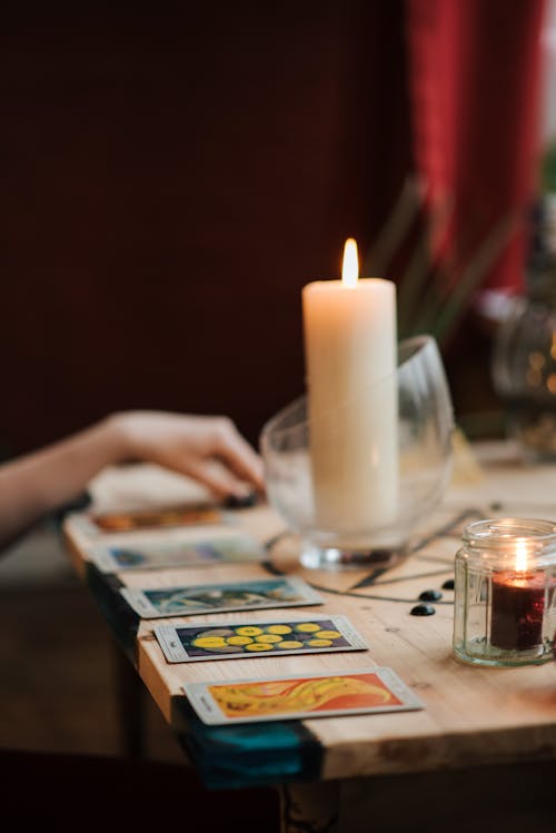 Crop soothsayer reading tarot cards near luminous candles