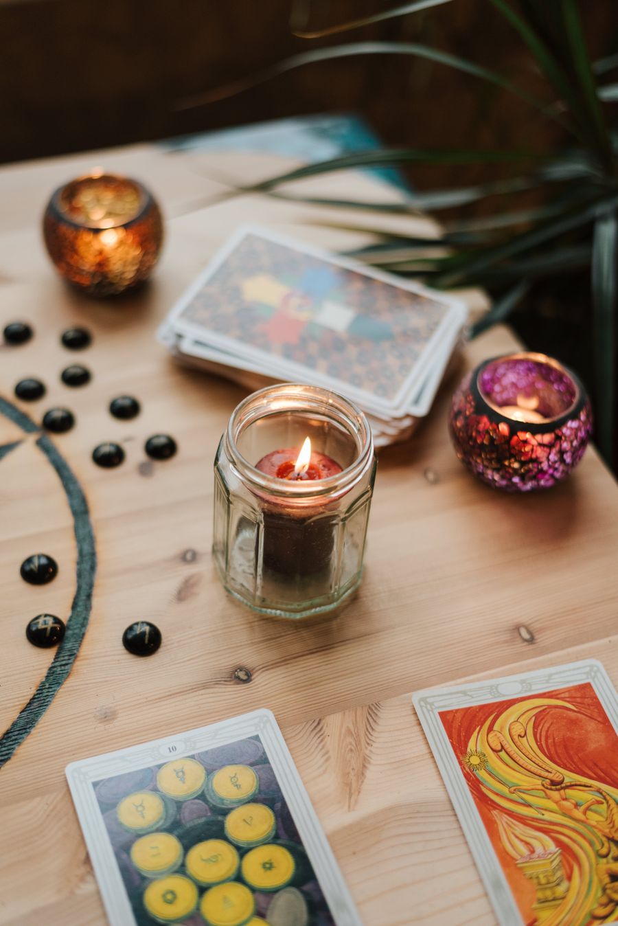 Velas encendidas junto a cartas de tarot sobre una mesa, ambiente ritual espiritual