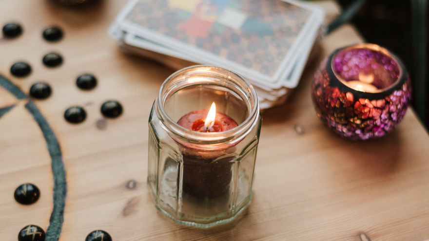 Burning candles beside tarot cards on a dark table, representing the calm, side-by-side process of comparing two Destiny Matrix charts