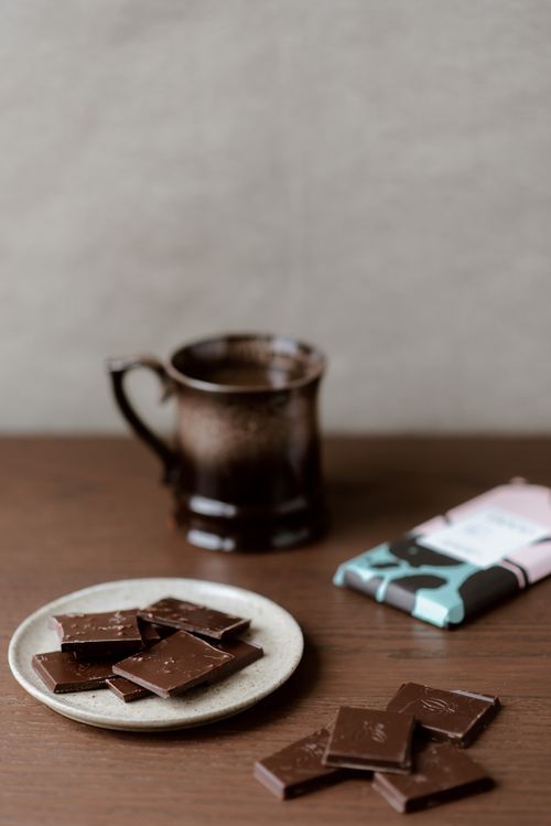 Free Composition of chocolate on ceramic plate and table near mug of coffee at home Stock Photo