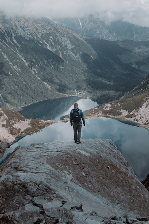 Man Standing on a Mountain near a Lake