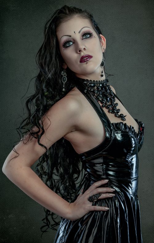 Free Striking portrait of a woman in gothic attire with long curly hair and dramatic makeup. Stock Photo