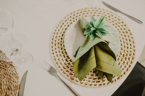 Free From above composition of green napkin in holder served on white plate on place mat near wineglasses before banquet Stock Photo