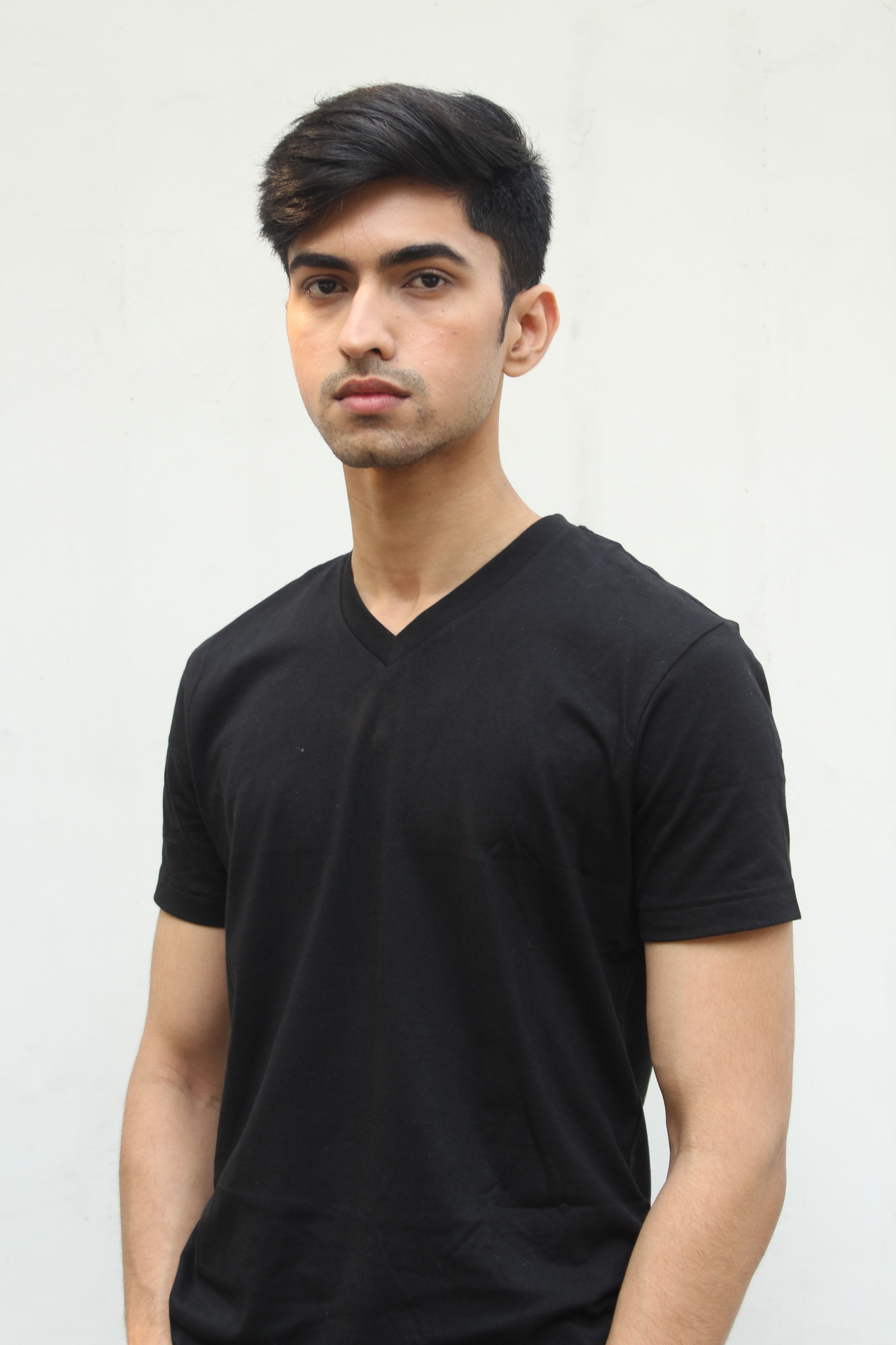 Portrait of a young man in a black shirt against a white background, looking pensive.