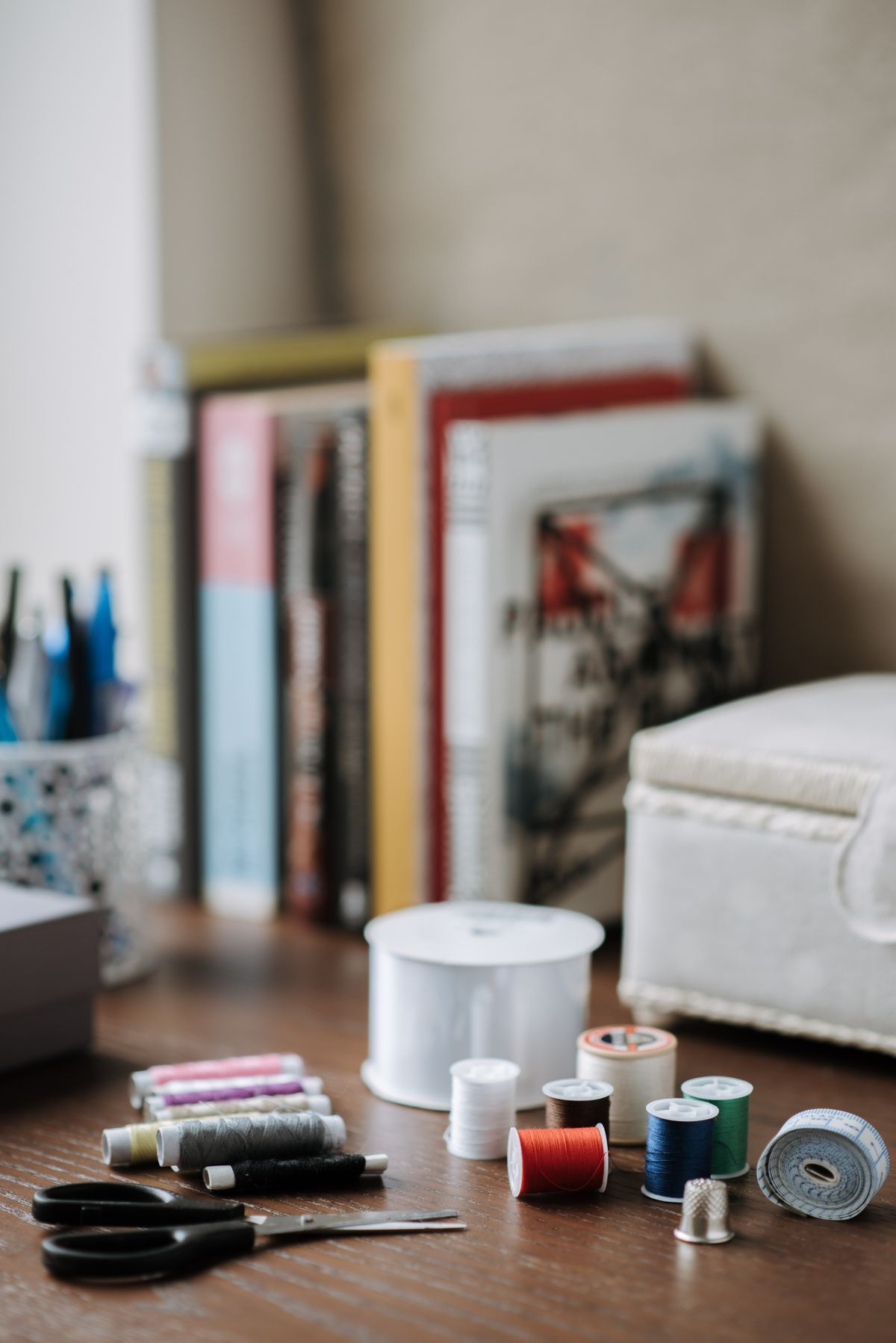 Threads and scissors near a thimble on a wooden table at home