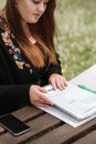 Crop woman sitting at table in park and reading documents