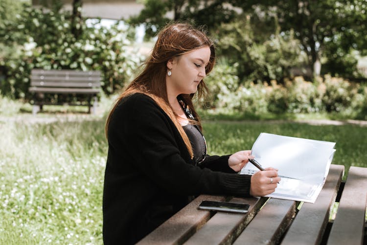 Woman Correcting Information In Paper With Pen