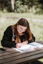 Happy content woman writing on paper on wooden table
