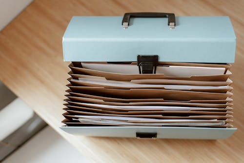Free From above of briefcase for documents with papers placed on wooden table in daytime Stock Photo