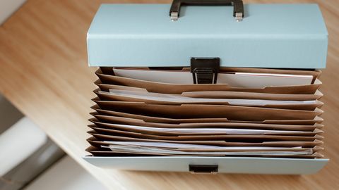 From above of briefcase for documents with papers placed on wooden table in daytime