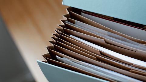 High angle of opened briefcase for documents with papers accosted in order placed on wooden table