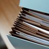 A close-up view of an expanding document folder on a wooden desk, symbolizing corporate filings and organization.