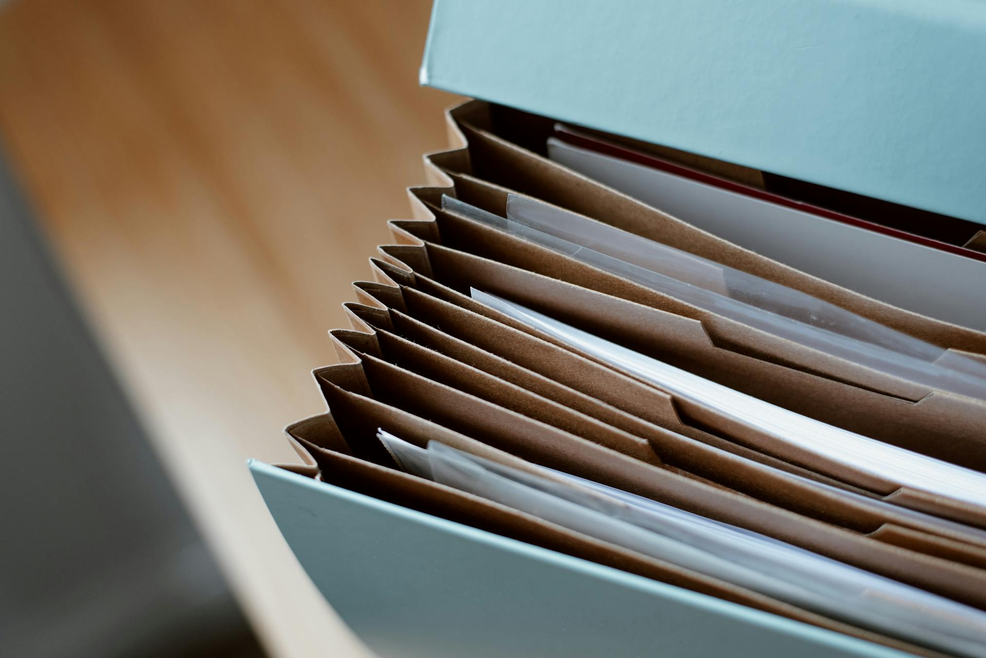 High angle of opened briefcase for documents with papers accosted in order placed on wooden table