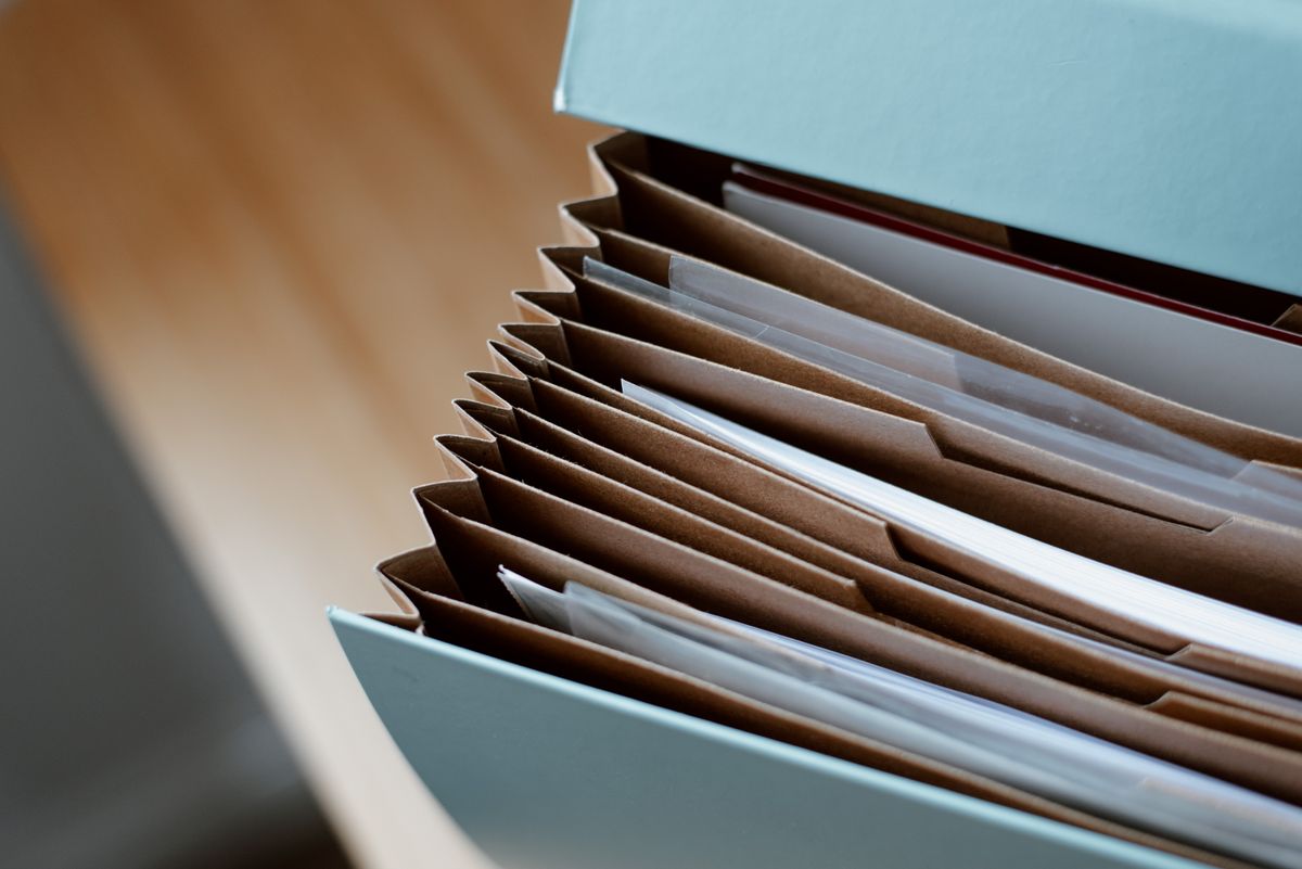 An open blue document case holding neatly separated paper files on a wooden table.