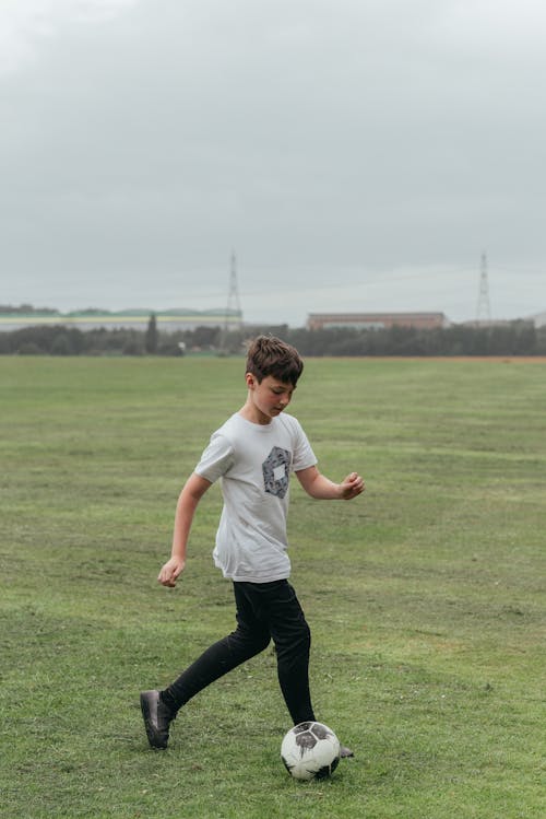 Boy playing football in green field