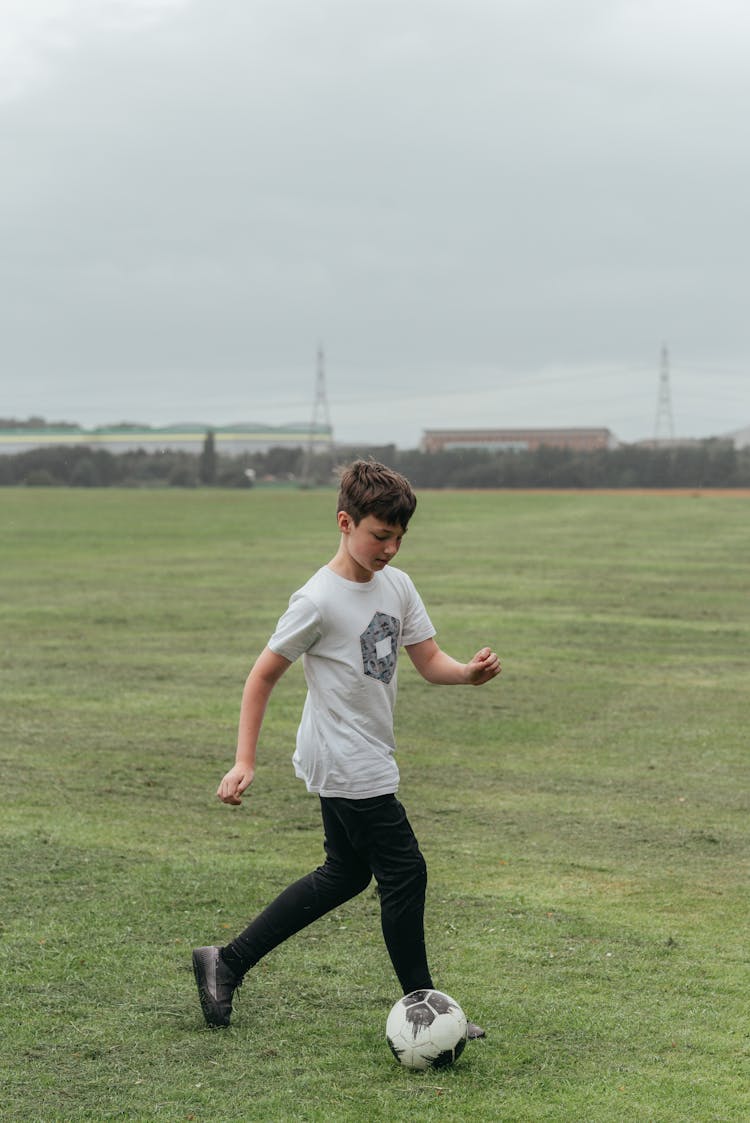 Boy Playing Football In Green Field