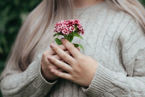 Peaceful female standing with pink flowers in hands