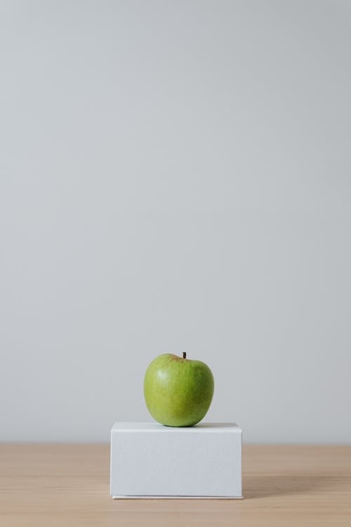 Green apple on cardboard box on white background