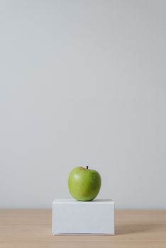 白色盒子上放着新鲜的青苹果，背景简洁，非常适合健康生活方式主题