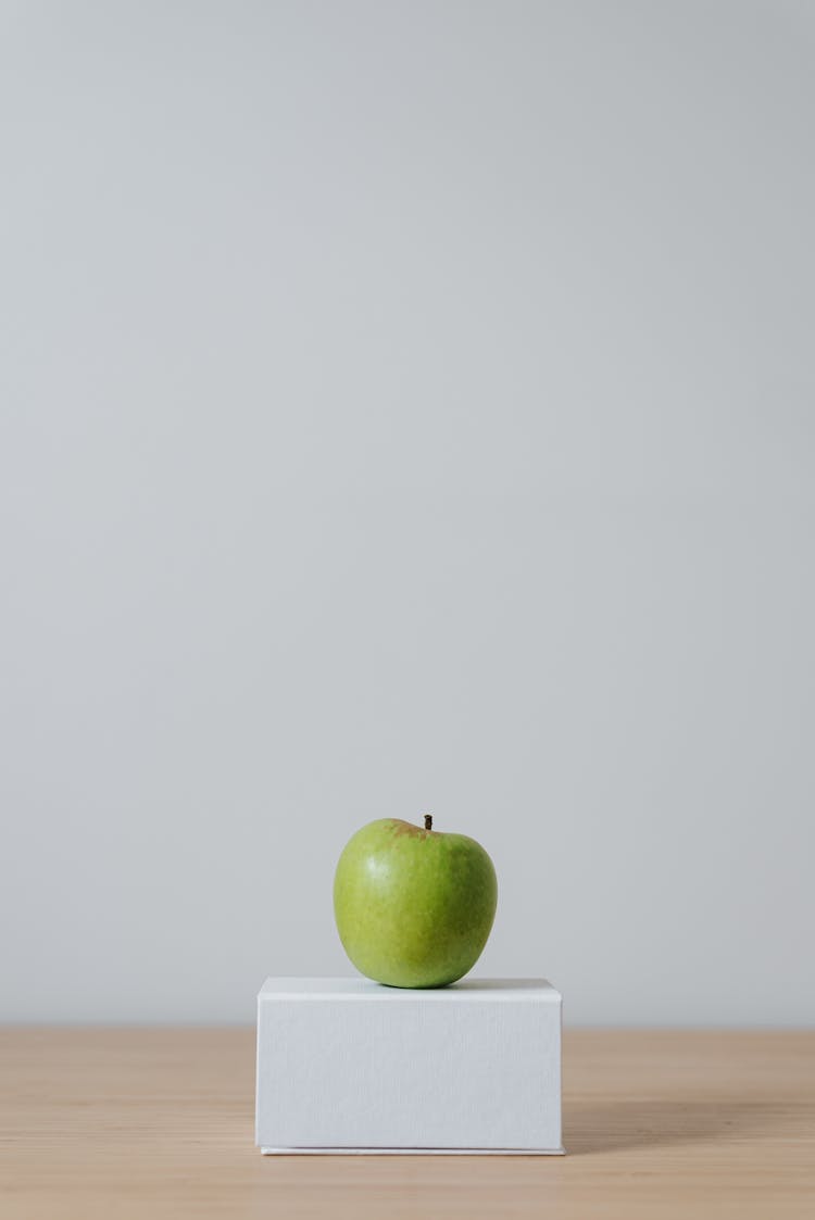 Green Apple On Cardboard Box On White Background