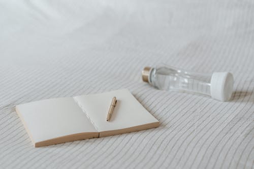 Empty notepad near decorative bottle on bed