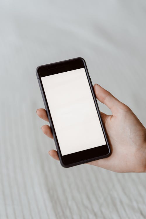 Faceless person demonstrating empty screen on smartphone