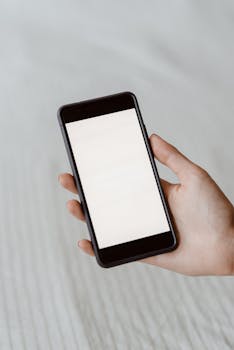 A close-up of a hand holding a smartphone with a blank screen, perfect for mockups.