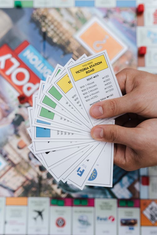 From above of crop anonymous player with set of cards with information playing board game