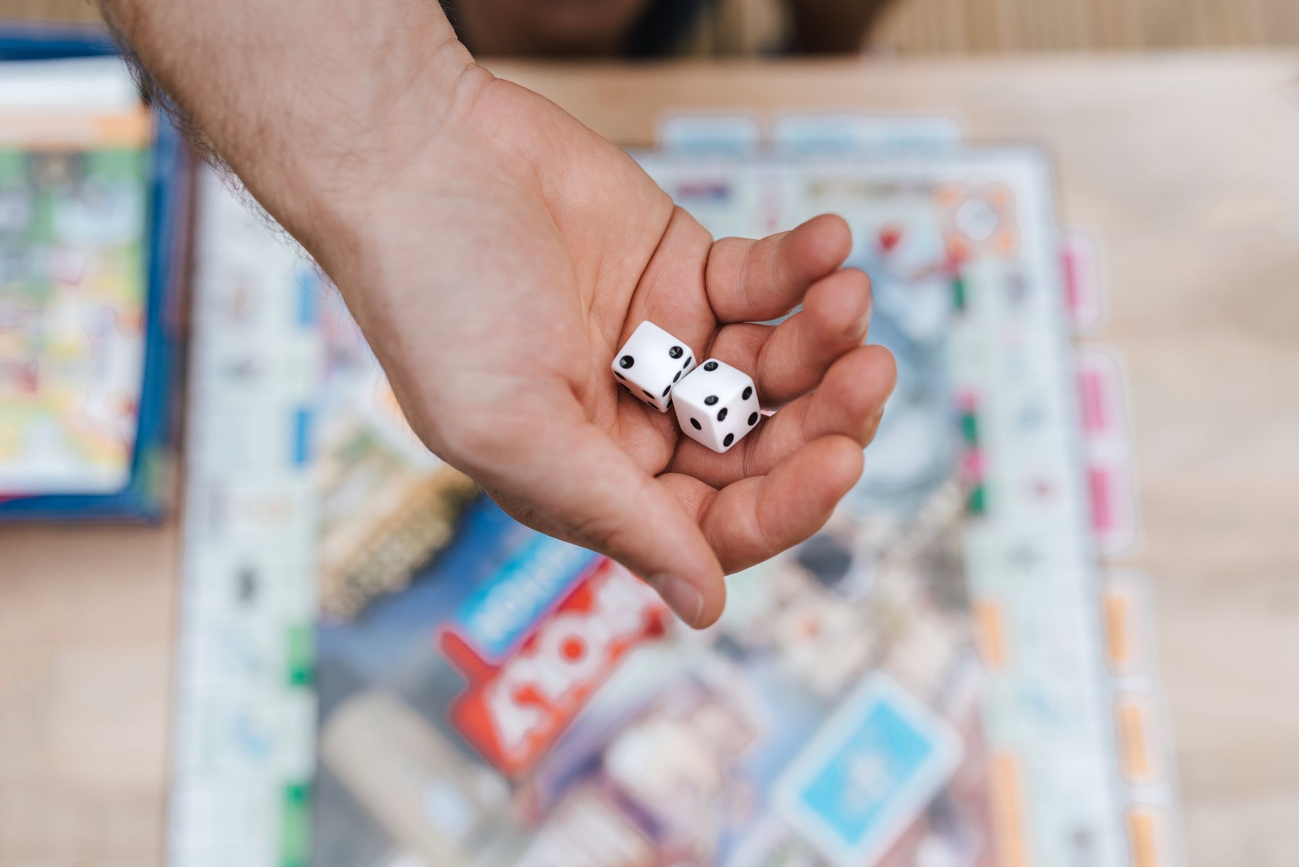From above of crop anonymous man preparing to roll dices while playing Monopoly in daylight
