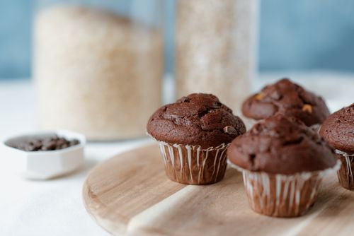 Free Tasty soft muffins with chocolate chips in paper liners on table on blurred background Stock Photo