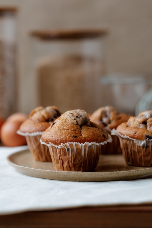 Free Yummy muffins with tender texture in baking cups on table near containers with ingredients Stock Photo