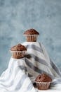 Composition of baked brown sweet muffins in forms placed on striped fabric in studio