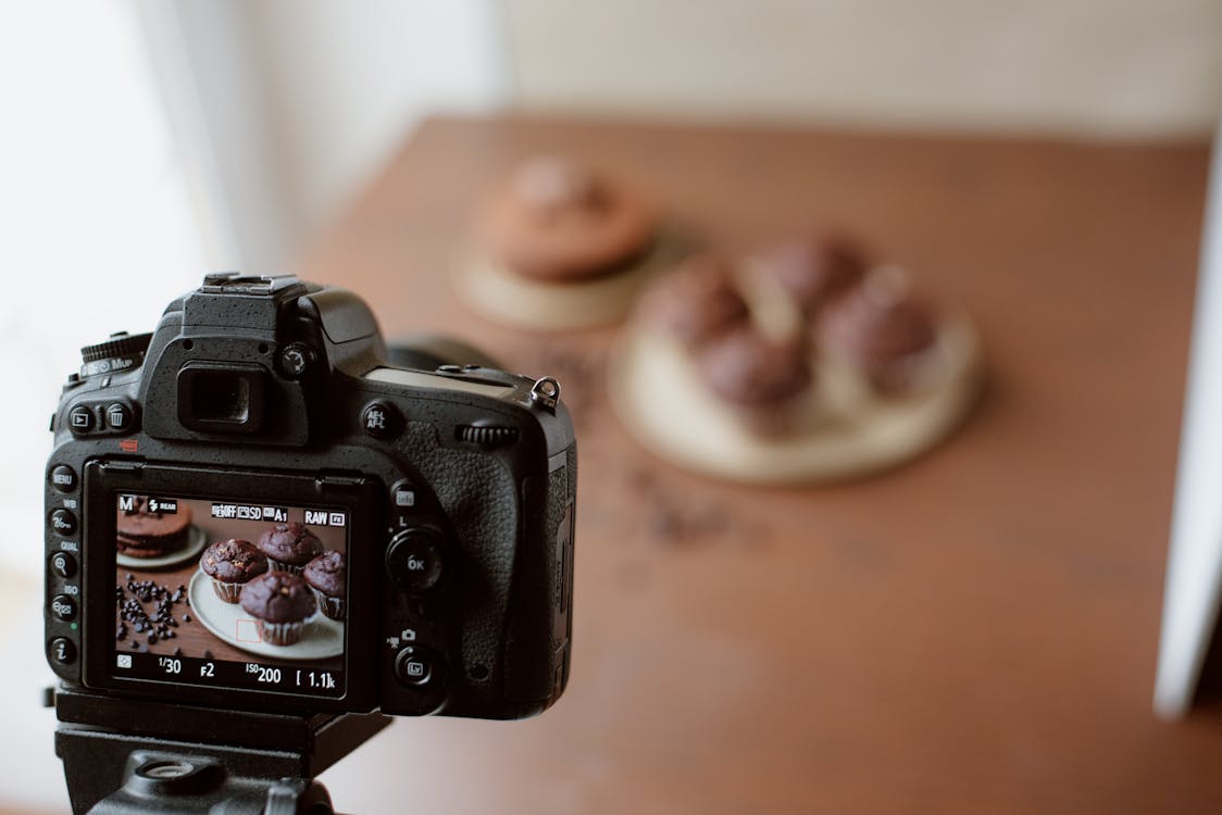 Screen of photo camera with photo of chocolate cupcakes