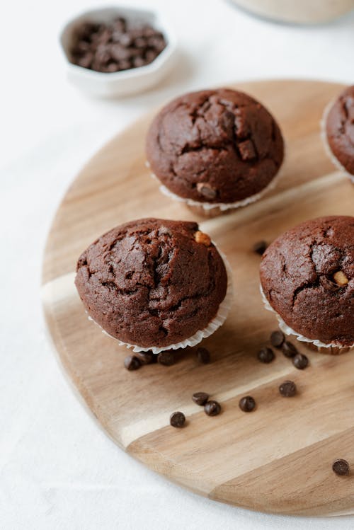 From above of appetizing chocolate muffins served on wooden board decorated with coffee beans and placed on table