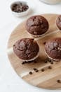 From above of appetizing chocolate muffins served on wooden board decorated with coffee beans and placed on table