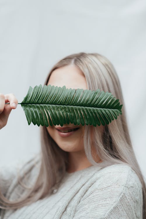 Smiling female covering face with green twig