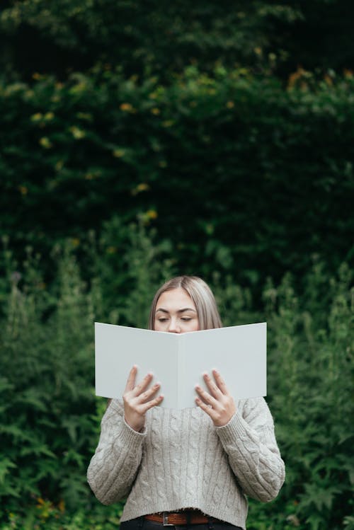 Serious woman reading interesting book in nature