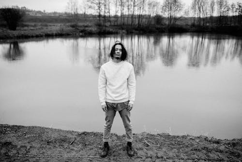 Confident Asian man standing on shore of lake